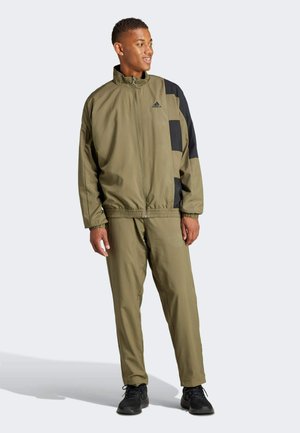 Tuta sportivo verde oliva con accenti neri; tessuto leggero; giacca con zip, pantaloni con vita elastica, caratterizzati da un design atletico moderno.
