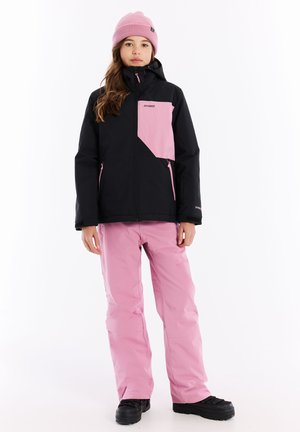 Schwarze und rosa Skijacke mit Kapuze und Reißverschlusstaschen, kombiniert mit rosa Schneehosen und schwarzen Winterstiefeln.