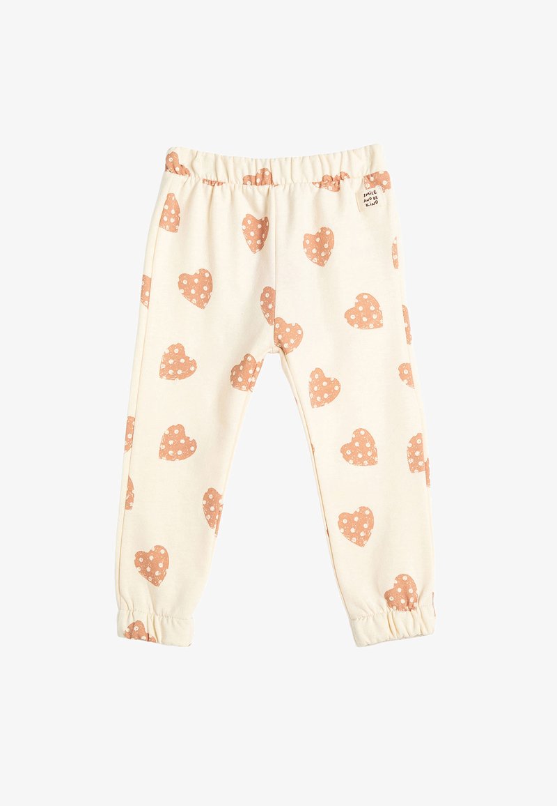 Leggings de algodón en crema con una cinturilla elástica, con corazones melocotón y lunares blancos en toda su superficie. Con puños en los tobillos.