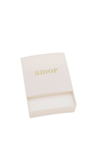 Małe, otwarte białe pudełko z złotymi literami "amor" na wieczku, ustawione na jednolitym białym tle.