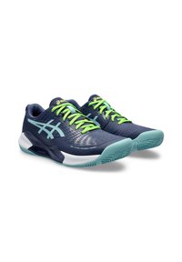 Zapatillas deportivas azul marino con acentos verdes, que cuentan con una parte superior texturizada, suela acolchada y un patrón distintivo en la suela para mayor tracción.