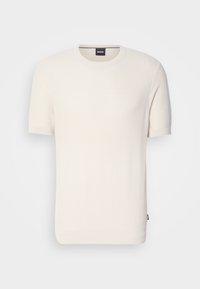 T-shirt a maniche corte di colore crema in maglia, con scollatura rotonda, caratterizzato da un tessuto testurizzato e un piccolo tag con logo sull'orlo.
