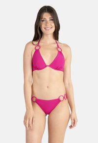 Bikini rose avec un haut triangulaire orné d'accents circulaires. Le bas présente un design similaire avec des détails circulaires sur les côtés. Texture lisse.