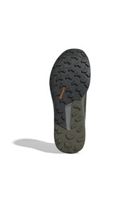 Semelle de chaussure en caoutchouc noir avec un motif de crampons pour une meilleure traction, dotée d'une base vert olive et d'un accent gris sur le côté.