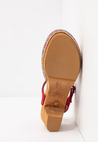 Sandale à plateforme rouge avec tige en tissu à motif floral, talon compensé en bois et semelle en caoutchouc texturée pour une bonne adhérence. La taille 37 est visible.