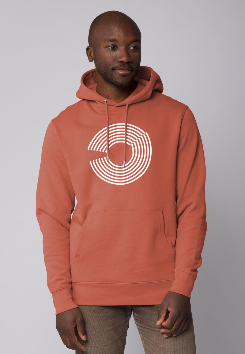 Roestkleurige hoodie met een groot wit cirkelvormig streepdessin aan de voorkant. Het heeft een capuchon met trekkoord en een voorzak in kangoeroestijl.