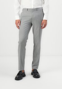Pantalon gris ajusté avec une finition texturée, coupe slim et poches latérales, associé à des mocassins noirs.