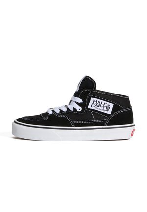 Fekete-fehér Vans Half Cab középmagas szintű gördeszkás cipő fehér fűzőkkel, fehér varrással és vastag fehér gumitalppal.