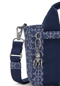 Borsa in tessuto blu navy con tessuto decorato, accenti testurizzati e un ciondolo a forma di scimmia in argento. Presenta una clip e una tracolla regolabile.