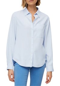 Light blue long-sleeve shirt made of smooth fabric with a pointed collar, front buttons, and a chest pocket. Curved hemline.