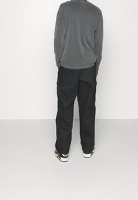 Gray long-sleeve shirt and black cargo pants, both with a relaxed fit. The outfit includes brown and white sandals. Plain background.
