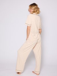 Beige pyjamasæt med korte ærmer, en afslappet pasform og sorte piping-detaljer ved kraven og manchetterne; let og luftig stof.