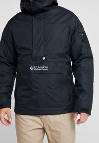 Czarna, kapturowa kurtka z półzamkiem, z przednią kieszenią, kieszenią na suwak na ramieniu oraz logo na piersi. Gładki, wodoodporny materiał.