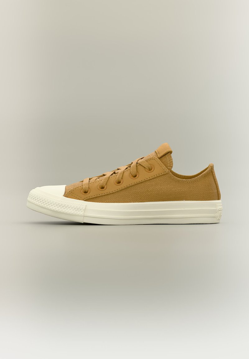 Χαμηλό παπούτσι από μπεζ καμβά με λευκή καουτσούκ σόλα και προστατευτικό μύτης, με κορδόνια στο ίδιο χρώμα, απεικονίζεται στο πλάι σε ουδέτερο φόντο.