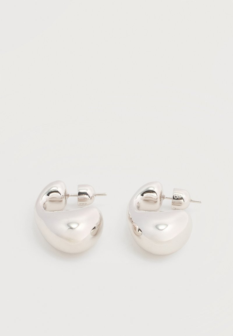 Ζευγάρι από λαμπερά ασημένια μεγάλα σκουλαρίκια κρίκους με κούμπωμα πίσω, σε απλό λευκό φόντο.