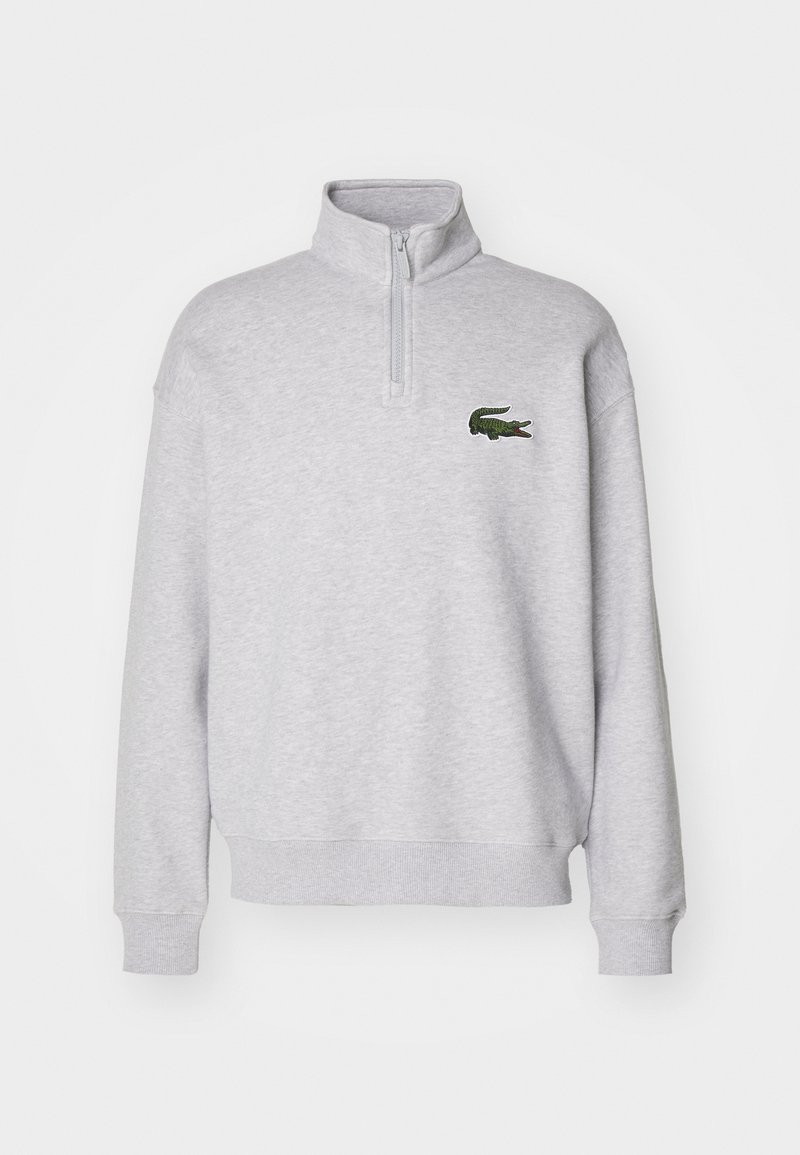 Sudadera de forro polar gris con cuello de media cremallera y puños de canalé, que presenta un logo de cocodrilo bordado en verde en el lado izquierdo del pecho.