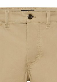Beige trousers featuring a front button closure, belt loops, and a zip fly. The fabric has a smooth texture with visible stitching details.