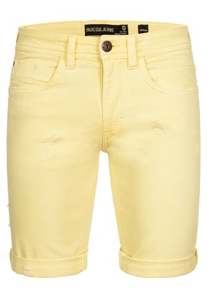 Gule denim shorts med et klassisk design, der har slidte detaljer, oprullede manchetter og knaplukning. Brandmærket er synligt på taljen.