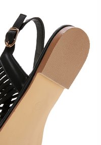 Black sandal featuring a textured rubber sole, woven upper design, ankle strap with gold buckle, and a smooth beige insole.