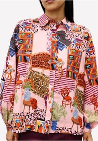 Hemd mit buntem Druck eines gemütlichen Wohnzimmers, das Bücherregale, einen Leopardenmuster-Sessel, gemusterte Teppiche, Pflanzen und dekorative Stühle zeigt.