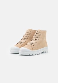 Sneaker alta in suede beige con suole in gomma bianche, punta rotonda e chiusura con lacci. Finitura testurizzata con dettagli di cucitura in vista.