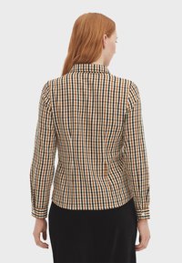 Brown and black checked button-up shirt with long sleeves and a collar, featuring a fitted design and visible seams.