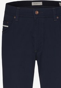 Námořnické modré kalhoty Bugatti s knoflíkovým zapínáním, poutky na opasek, předními kapsami a detailem s logem na pravé kapse.