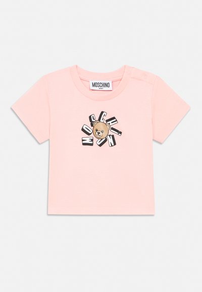 Pink short-sleeve baby shirt with a teddy bear head and scattered black-and-white letters spelling "Moschino" on the front.