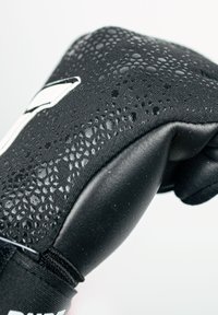 Schwarze Sporthandschuhe mit einer strukturierten Stoffoberfläche und Perforationen sowie einem glatten Handflächenbereich. Enthält weiße Markenverzierungen.