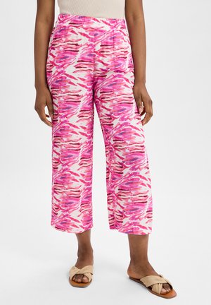 Weite Hosen mit einem rosa und weißen abstrakten Muster, featuring einen elastischen Bund und leichten Stoff. Kombiniert mit beigen Riemchensandalen.