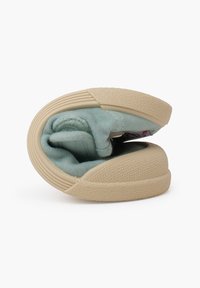 Scarpa in tela azzurra, piegata, con suola in gomma beige textured e interno morbido, che mostra un design minimale senza decorazioni.