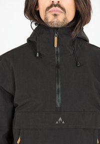 Vêtements d'extérieur noirs avec un col montant, une fermeture éclair et des cordons de serrage ajustables. Présente une poche avant et un logo de marque en bas.