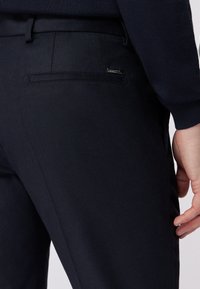 Marineblaues Hosenpaar aus glattem Stoff, ausgestattet mit einer Gesäßtasche mit einem dezenten Logo-Tag. Fein verarbeitet mit einem geraden Beinausschnitt.