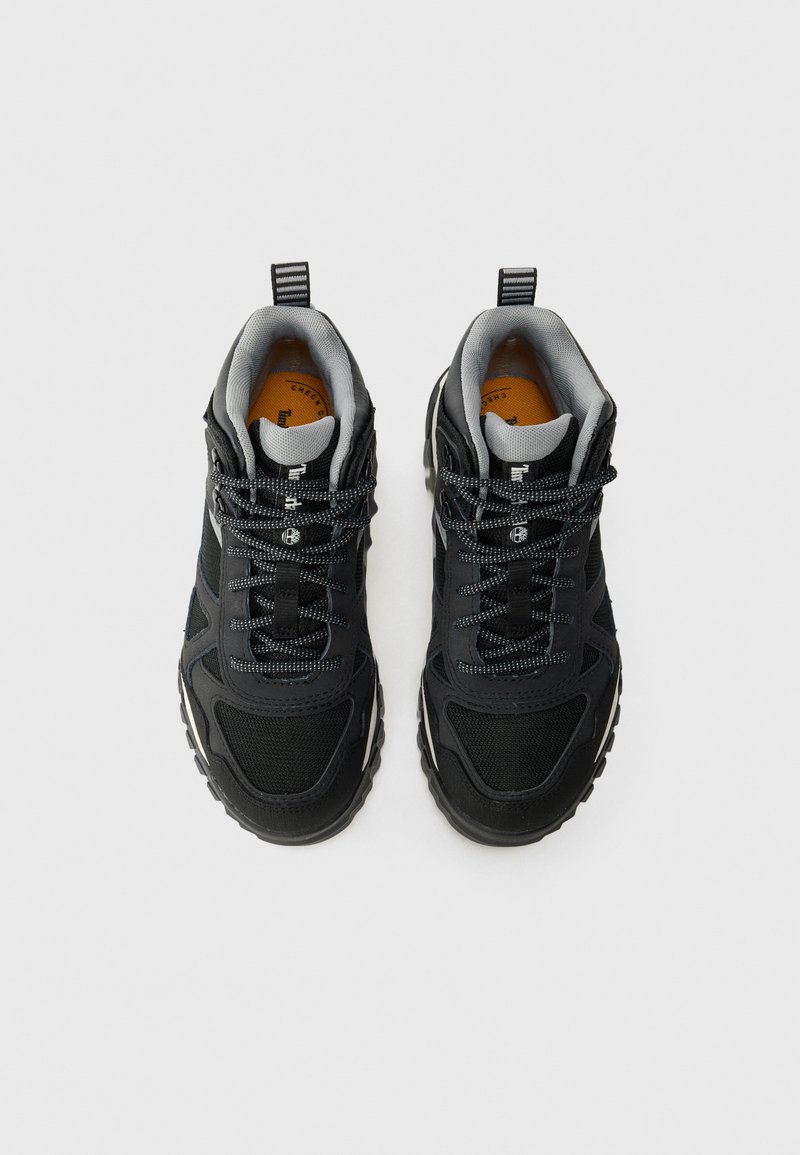 Une paire de baskets de sport noires et grises avec des semelles texturées et des lacets réfléchissants, vue de dessus sur un fond blanc.