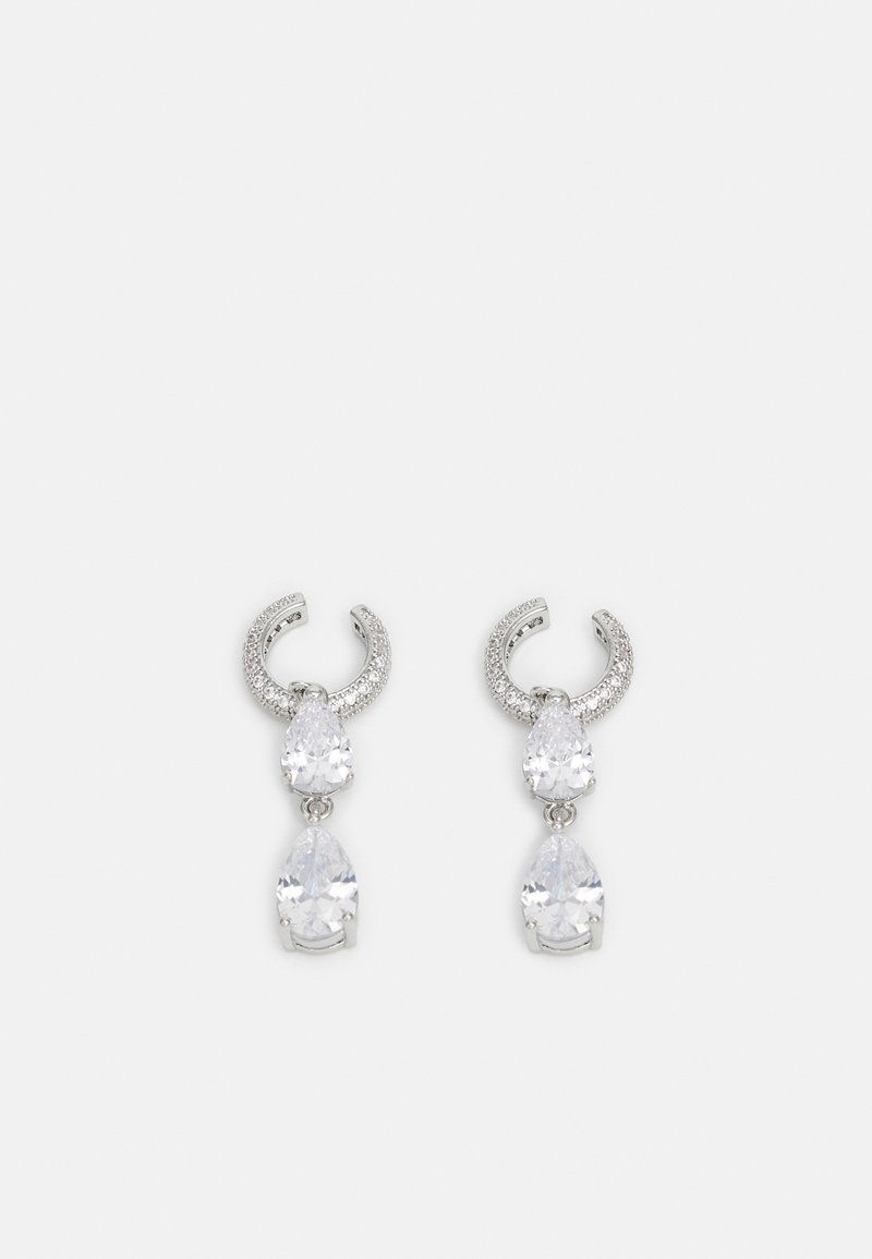 Boucles d'oreilles en argent avec un design de créole texturée, ornées de deux cristaux en forme de goutte d'eau transparents et d'un plus petit cristal carré en bas.