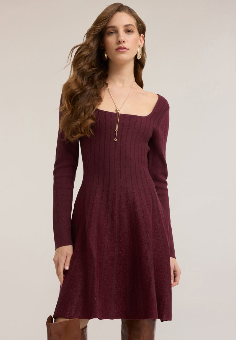 Weinrotes, geripptes Kleid mit quadratischem Ausschnitt und langen Ärmeln, das unterhalb der Taille ausgestellt ist, gefertigt aus weichem, strukturiertem Stoff.