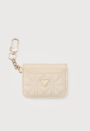 Porte-cartes matelassé beige avec logo Guess doré et mousqueton porte-clés à chaîne sur fond blanc.