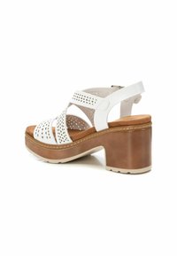 Sandalo bianco in pelle con design a intaglio e cinturino alla caviglia regolabile. Caratterizzato da tacco spesso marrone e suola beige chiaro per ulteriore comfort.