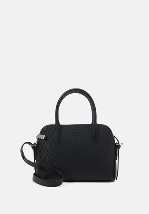 Bolso de mano negro con una superficie texturada, forma redondeada, dos asas superiores y una correa de hombro desmontable. Presenta un sutil detalle de logo.