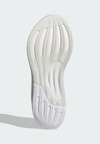 Shoe sole in white rubber with textured grip patterns, featuring elongated grooves and rounded edges for flexibility and traction.