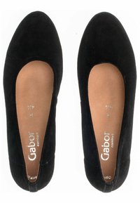 Black suede ballet flats with a rounded toe, featuring a smooth, soft texture and an open-sided design. Inside is a tan insole with silver branding.