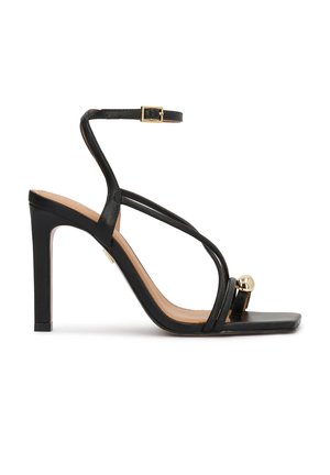 Black high-heeled sandal with ankle strap, slim toe loop featuring a gold ball accent, and a square open toe design.