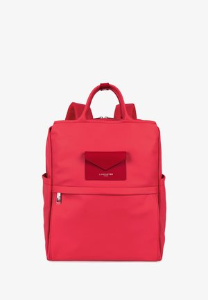Sac à dos en nylon rouge avec une poche à rabat à l'avant, une poignée supérieure, des bretelles rembourrées et une fermeture éclair. Texture lisse et design minimaliste.