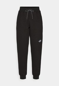 Jogging en noir à motif gaufré avec taille élastique, cordon de serrage et bas ribbés. Présente un petit logo blanc sur la jambe gauche.