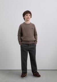 Brown knitted sweater with a ribbed hem, gray corduroy pants, and brown shoes with yellow accents. Simple design, comfortable fit.