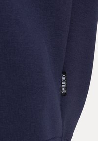 Námořnická modrá mikina ze žerzejové tkaniny s texturovaným povrchem. Označení na bočním švu s textem "SILLOOXX" vyšitém na černé etiketě.