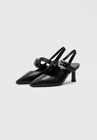 Μαύρα δερμάτινα παπούτσια slingback με μυτερή μύτη, μικρό τακούνι τύπου block και διακοσμητικό λουράκι με πετράδια. Ομαλή υφή και κομψός σχεδιασμός.