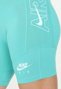 Tyrkysové sportovní šortky s hladkým povrchem. Mají bílé logo "NIKE" a "AIR". Elastický materiál a přiléhavý střih.
