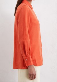 Camicia a maniche lunghe con bottoni in lino arancio brillante, caratterizzata da un colletto, una vestibilità su misura e polsi con bottoni.