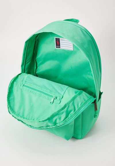 Πράσινος υφασμάτινος σακίδιο με φερμουάρ μπροστινής τσέπης και εσωτερική ετικέτα. Ο σχεδιασμός διαθέτει μαλακή υφή και στρογγυλή κορυφή.